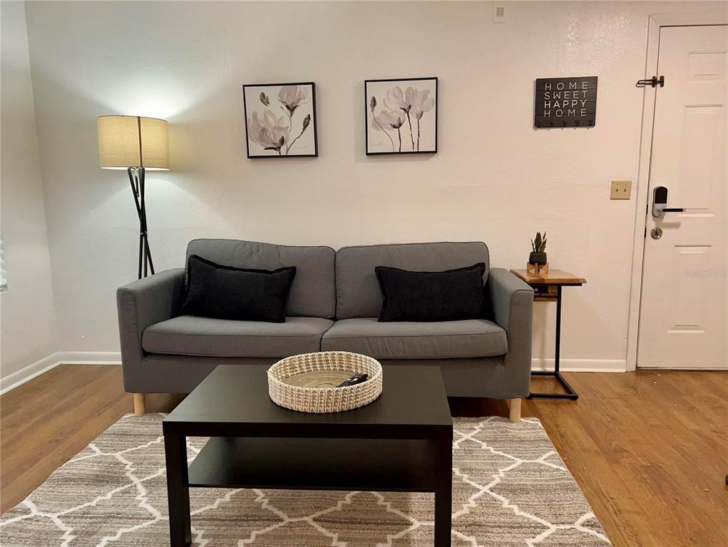 A living room features a grey sofa, a black coffee table, and wall art — 11526 WESTWOOD BOULEVARD UNIT 723, ORLANDO, FL