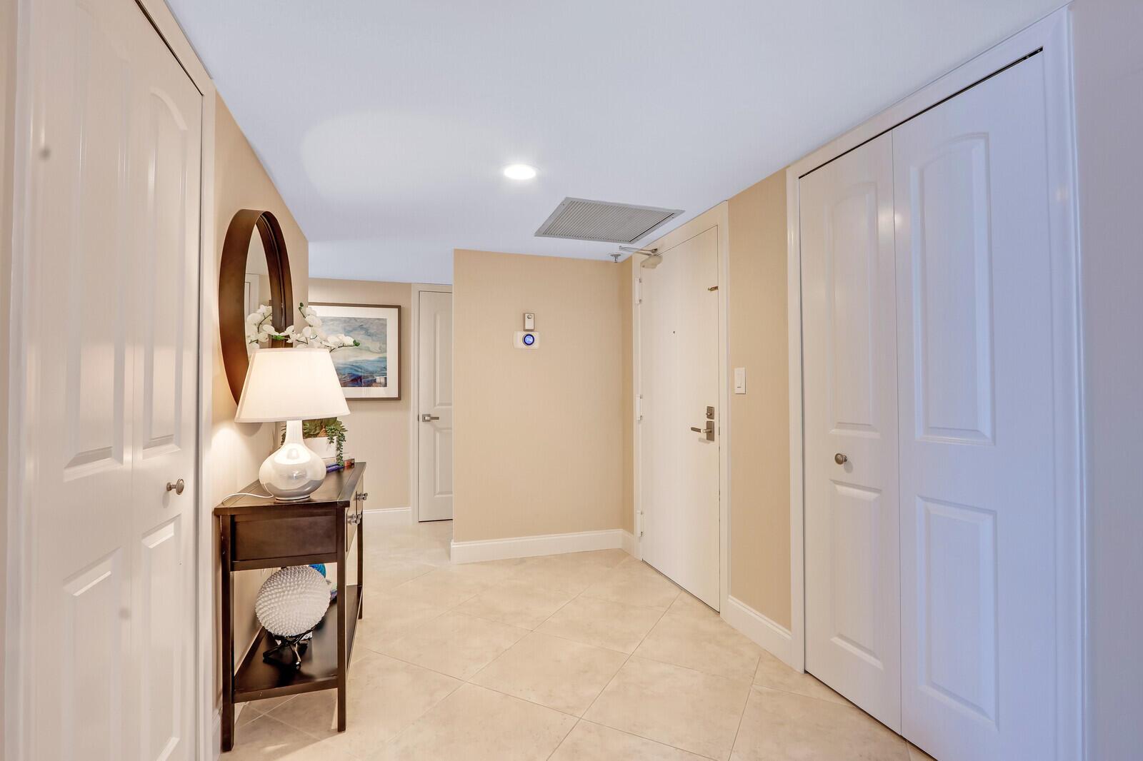 A bright entryway features beige walls, tile flooring, a console table, and white closet doors — 4200 N Ocean Drive # 802, Singer Island FL 33404, SINGER ISLAND, FL