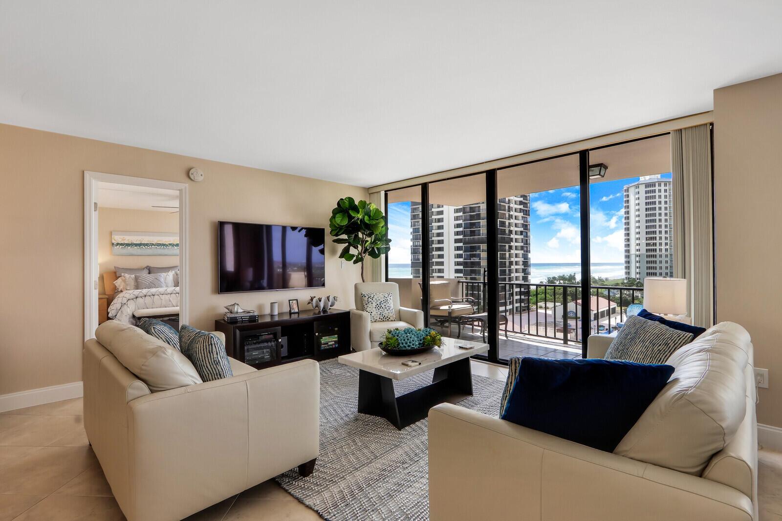 A living room features two cream sofas, a coffee table, and a balcony with ocean views — 4200 N Ocean Drive # 802, Singer Island FL 33404, SINGER ISLAND, FL
