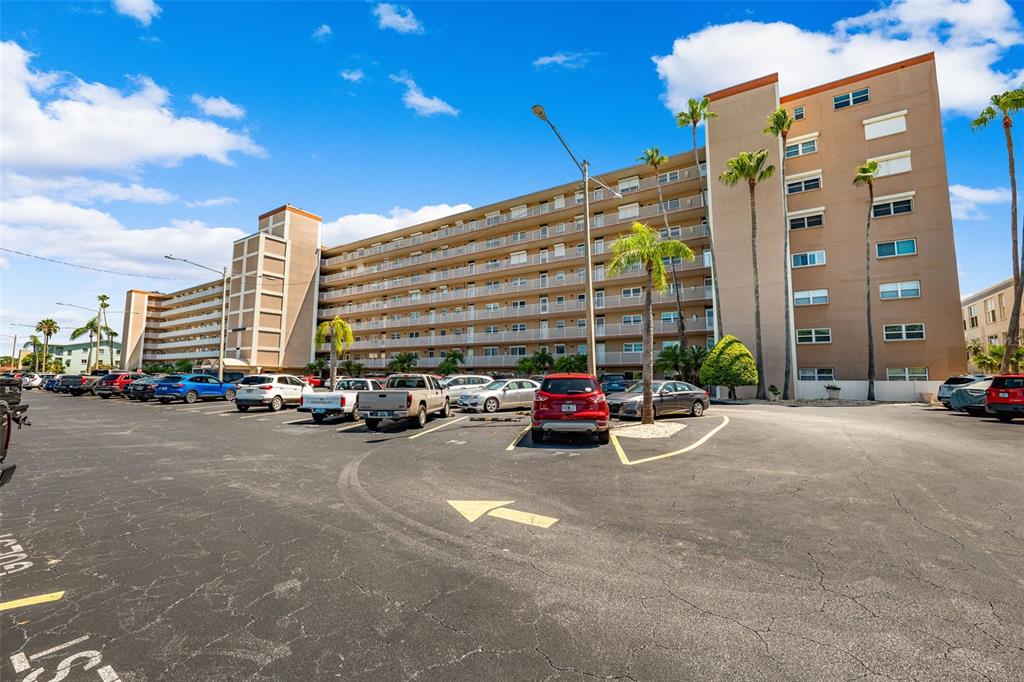 A multi-story apartment building with a parking lot in the foreground under a blue sky — 1847 SHORE DRIVE S UNIT 101, ST PETERSBURG, FL