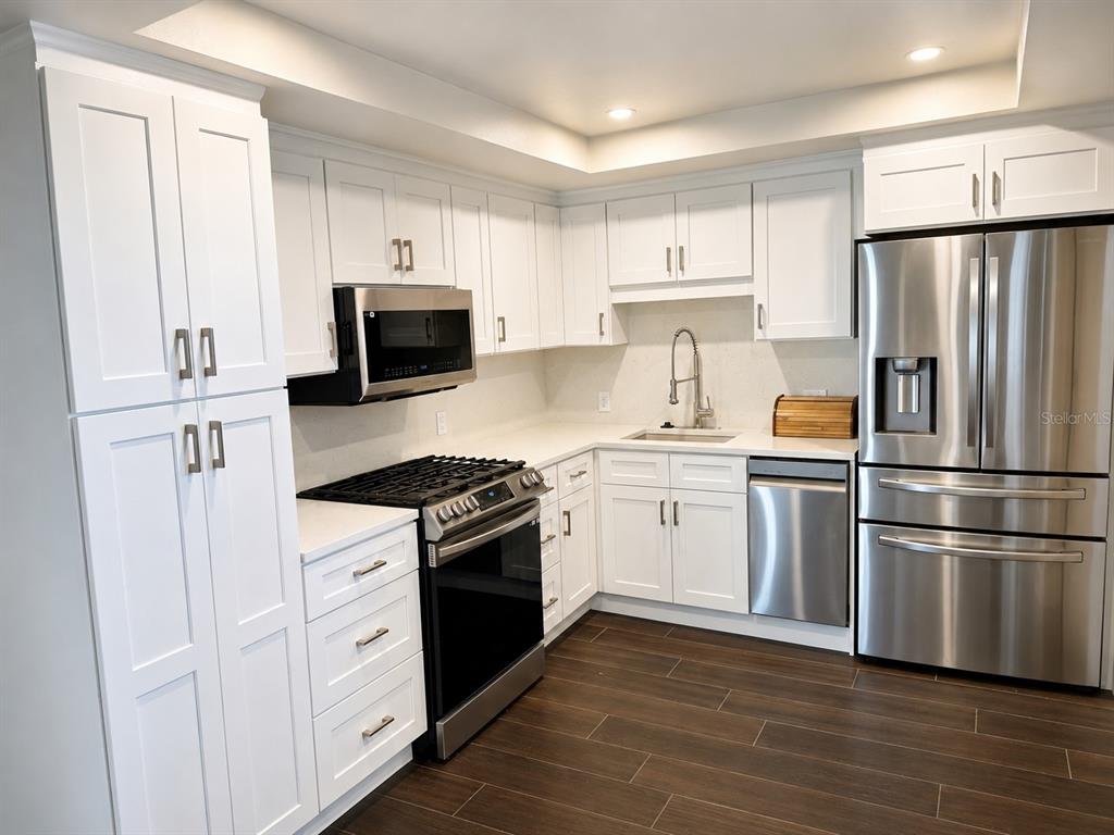 A kitchen with white cabinets, stainless steel appliances, and dark wood-look flooring — 1847 SHORE DRIVE S UNIT 101, ST PETERSBURG, FL