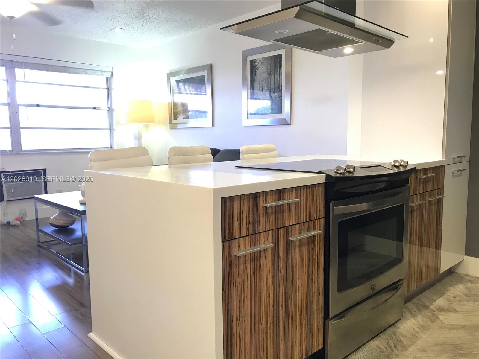 A modern kitchen with a breakfast bar and dining area featuring white furniture and flooring — 2915 Plunkett St # 10D, Hollywood FL 33020, HOLLYWOOD, FL