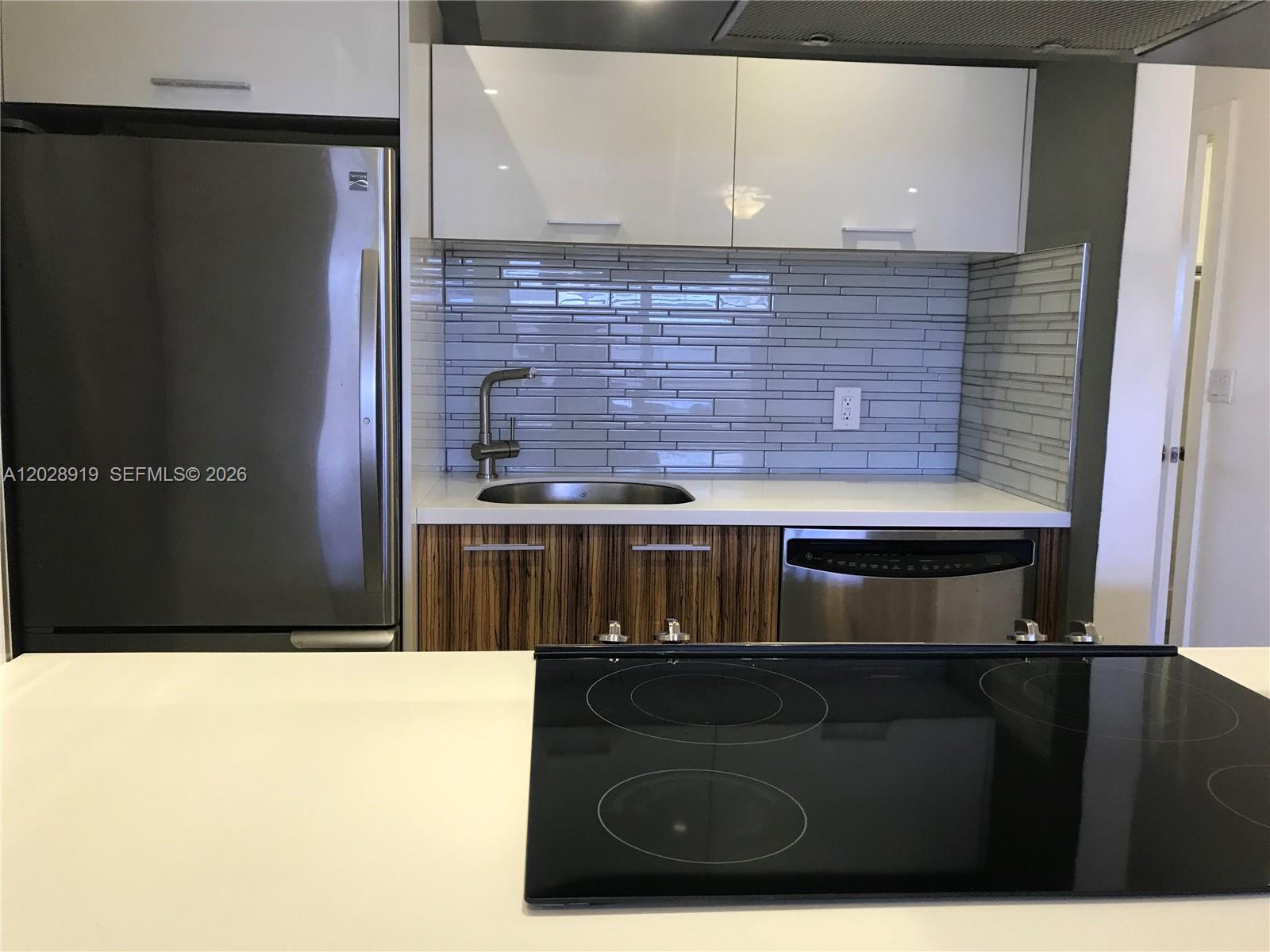 A kitchen island with wood-grain cabinets and a white countertop sits before a stainless stove — 2915 Plunkett St # 10D, Hollywood FL 33020, HOLLYWOOD, FL