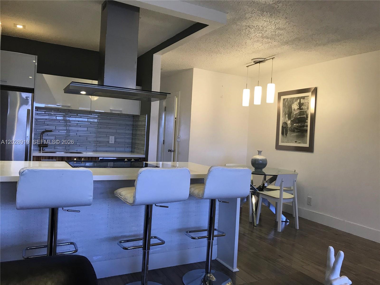 A galley kitchen features stainless steel appliances, wood-grain cabinets, white countertops, and herringbone-patterned flooring — 2915 Plunkett St # 10D, Hollywood FL 33020, HOLLYWOOD, FL