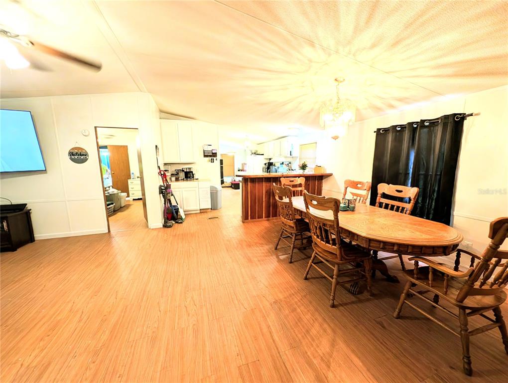 A dining area with a wooden table and chairs opens into a kitchen with cabinets — 23880 NE 121ST LANE, FORT MC COY, FL