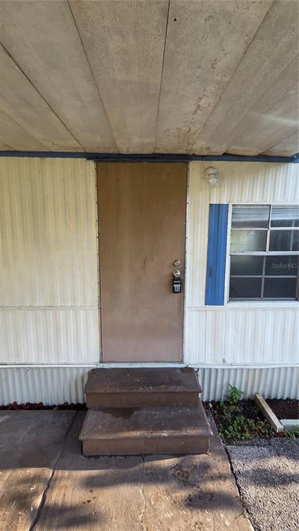 The exterior of a mobile home features a brown door, two steps, and a window — 2735 W 10TH STREET UNIT 1, LAKELAND, FL