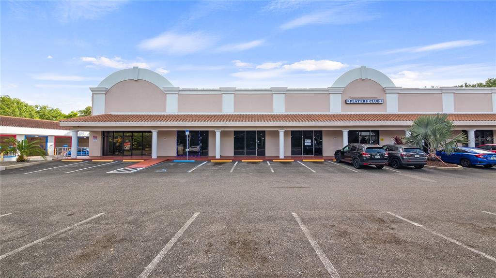 A single-story commercial strip mall with a parking lot in the foreground — 25010 US HIGHWAY 27 UNIT EF /67, LEESBURG, FL