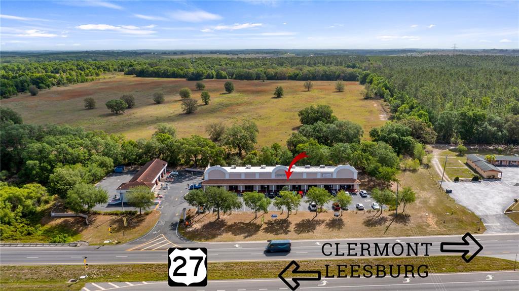 An aerial view shows a commercial strip mall located along a highway — 25010 US HIGHWAY 27 UNIT EF /67, LEESBURG, FL