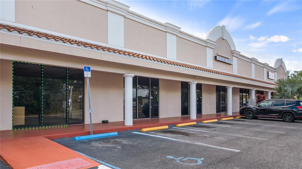 A view of a commercial strip mall exterior with a parking lot and handicap space — 25010 US HIGHWAY 27 UNIT EF /67, LEESBURG, FL