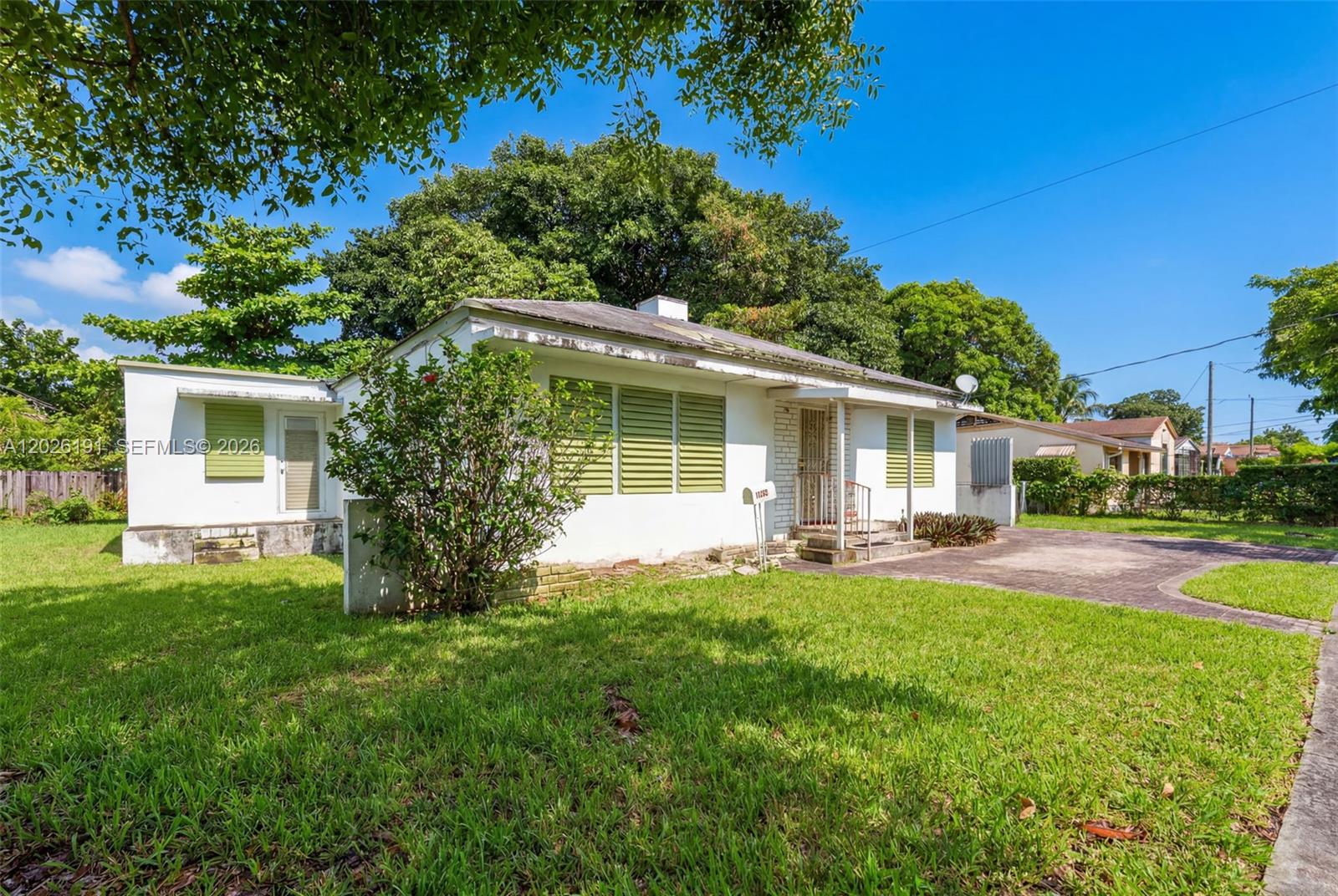 A single-story white house with green shutters sits on a grassy lot with trees — 1279 NW 41st St, Miami FL 33142, MIAMI, FL