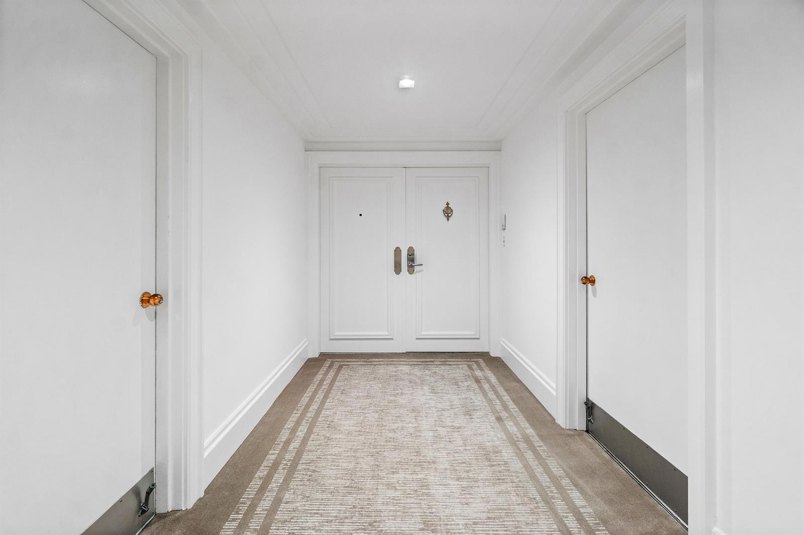 A white hallway features a double door entrance, carpeted flooring, and two side doors — 150 Bradley Place # 101, Palm Beach FL 33480, PALM BEACH, FL