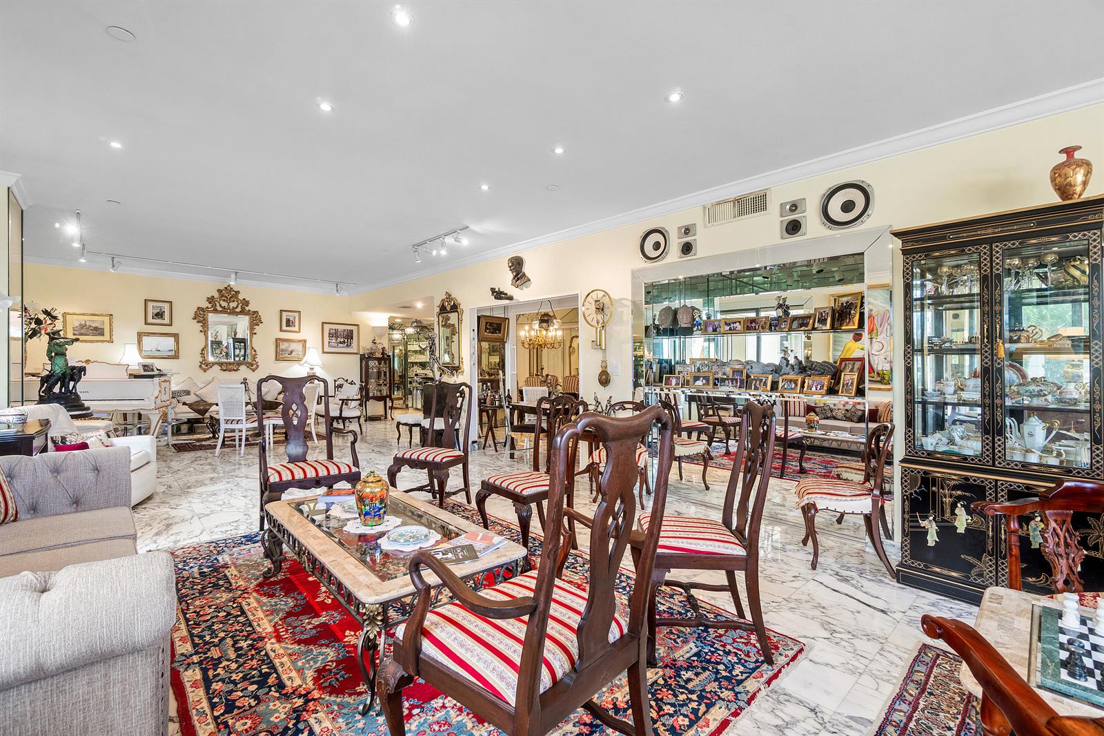 A spacious living room features marble floors, ornate wooden chairs, and a large display cabinet — 150 Bradley Place # 101, Palm Beach FL 33480, PALM BEACH, FL