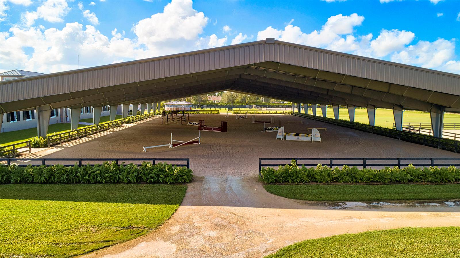 An aerial view of an open-air equestrian riding arena with jumps under a large roof — 5219 130th Avenue S, Wellington FL 33449, WELLINGTON, FL