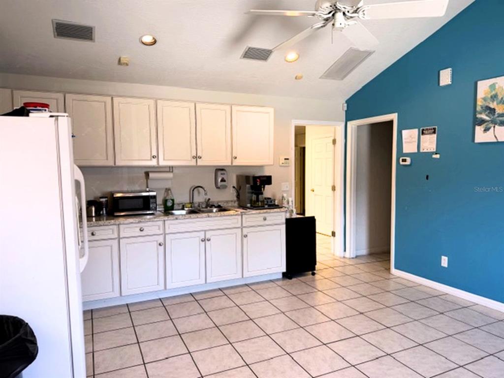 A kitchen with white cabinets, light countertops, tile flooring, and a blue accent wall — 233 12TH STREET SW, LARGO, FL