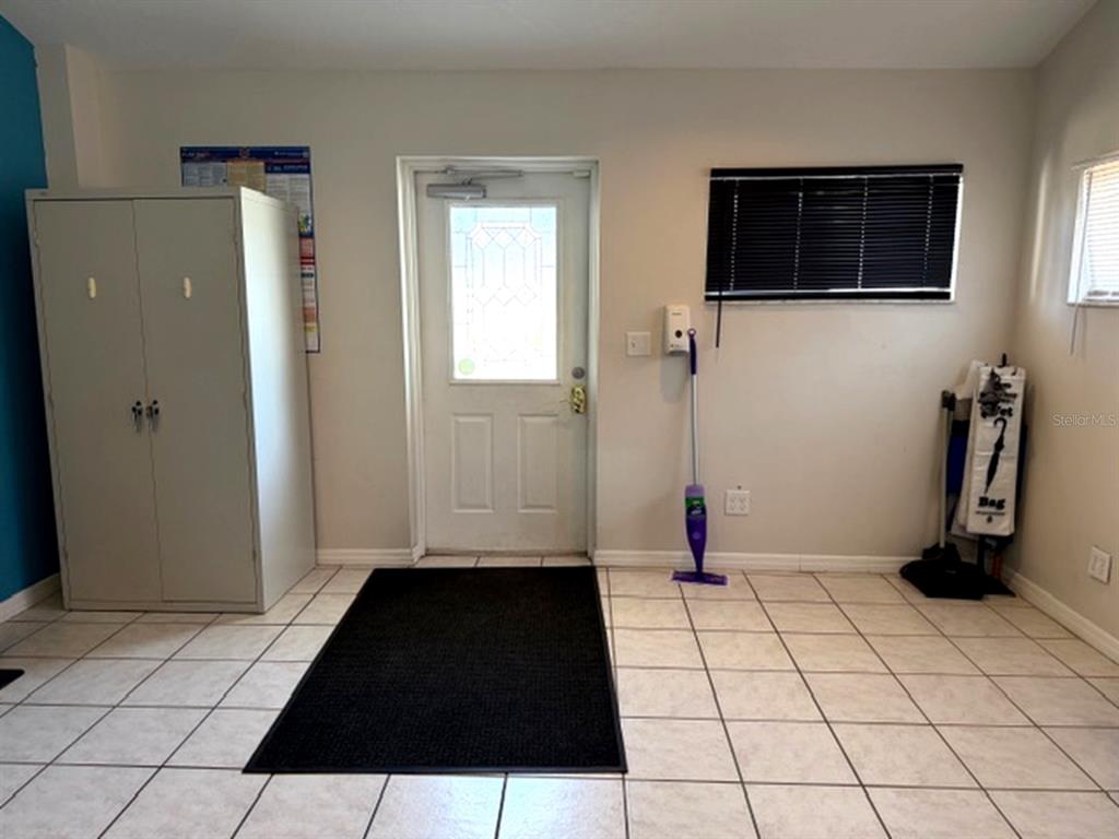 A tiled room features a white door, a metal cabinet, and a black floor mat — 233 12TH STREET SW, LARGO, FL