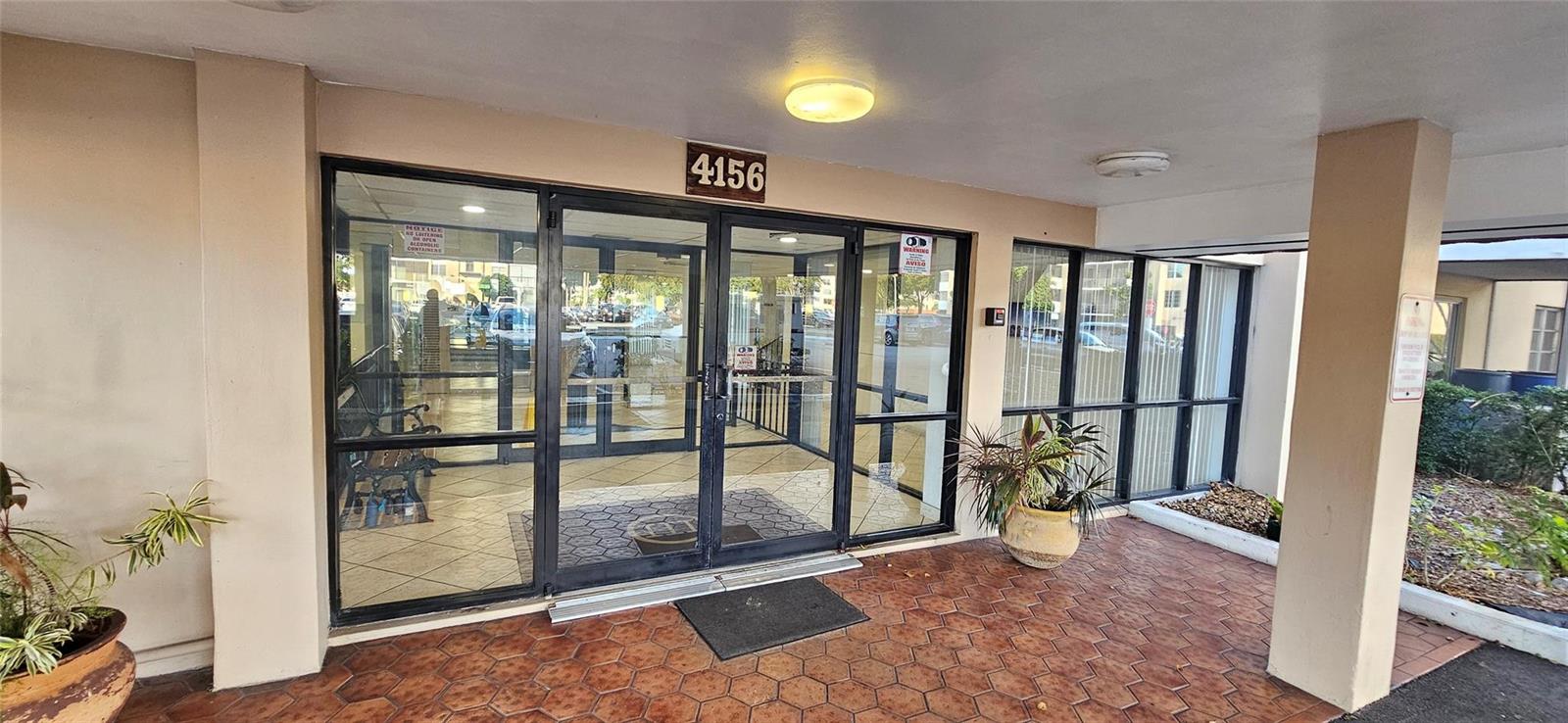The exterior entrance features double glass doors under a covered walkway with tiled flooring — 4156 Inverrary Drive # 204, Lauderhill FL 33319, LAUDERHILL, FL