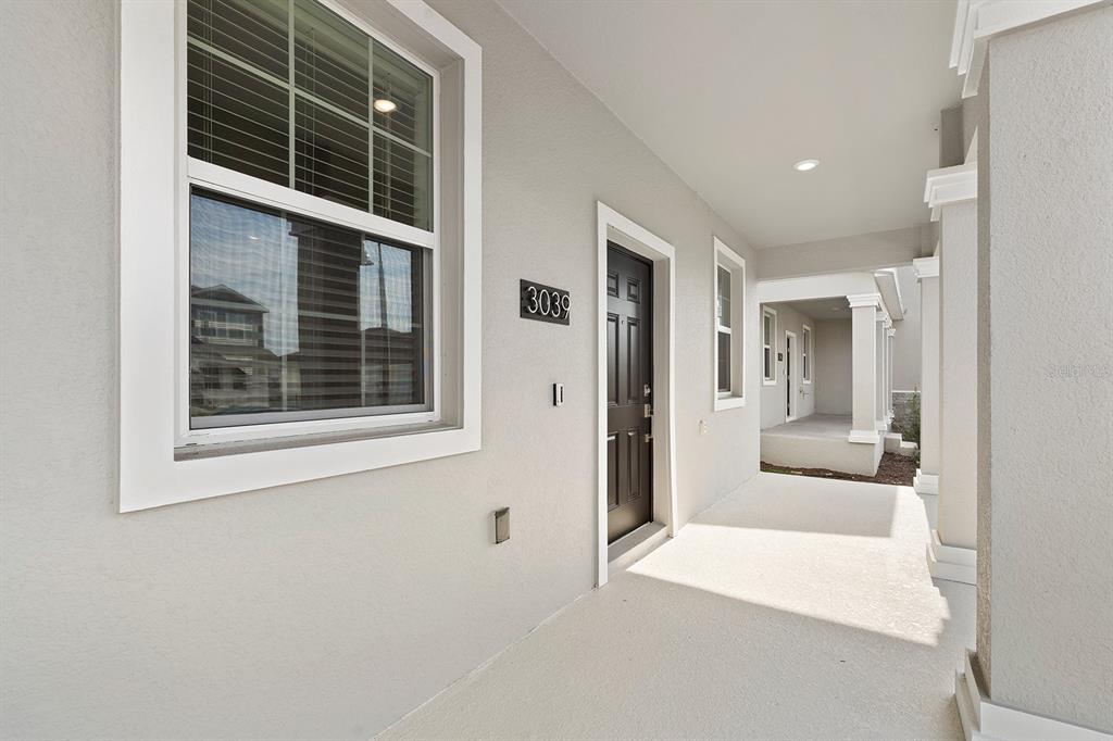A covered porch with a dark front door, a window, and light-colored exterior walls — 3039 ELLA WAY, ST CLOUD, FL