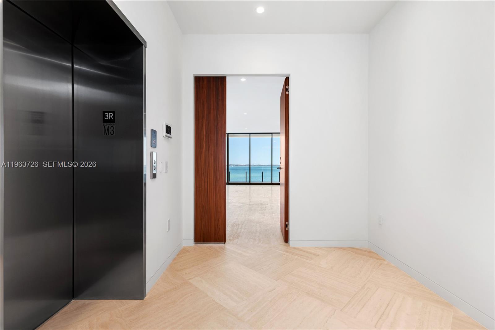 An elevator opens into a minimalist foyer with light wood flooring leading to a water view — 5 Grove Isle Dr # M303, Miami FL 33133, MIAMI, FL