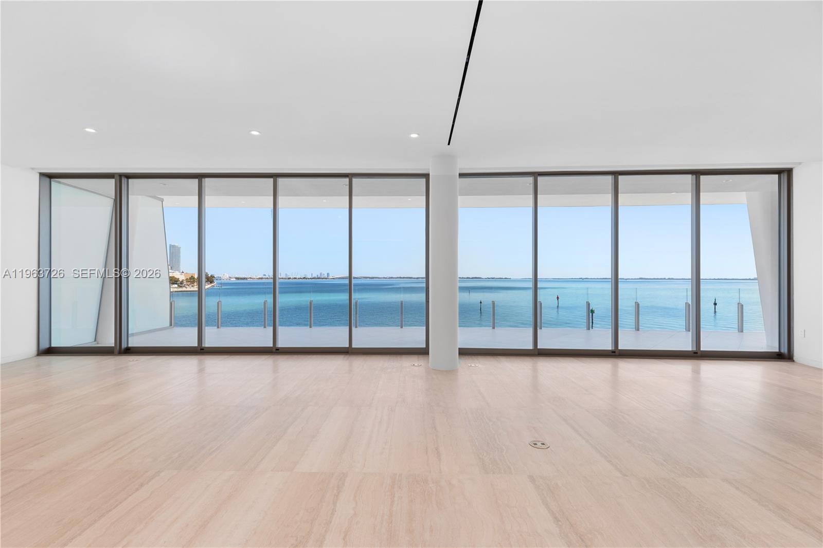 An empty room with light wood flooring and floor-to-ceiling windows overlooking the ocean — 5 Grove Isle Dr # M303, Miami FL 33133, MIAMI, FL