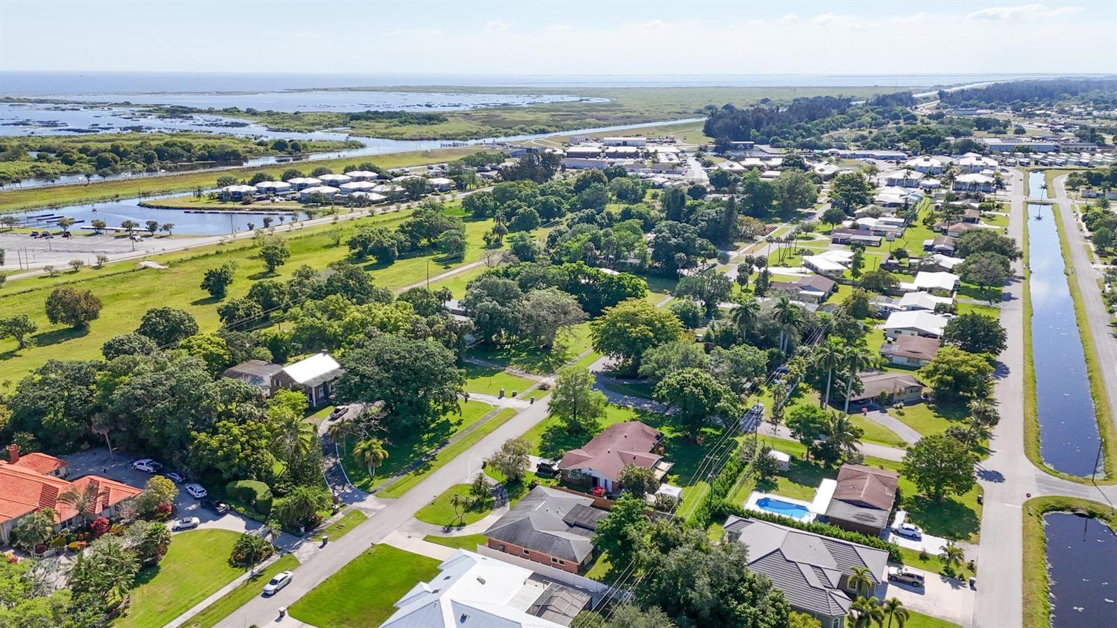 An aerial view shows a residential neighborhood with houses, trees, and a canal — 534 E Del Monte Avenue, Clewiston FL 33440, CLEWISTON, FL