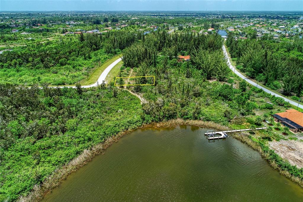 An aerial view shows a rectangular plot of land outlined in yellow near a lake — 15286 INGRAHAM BOULEVARD, PORT CHARLOTTE, FL