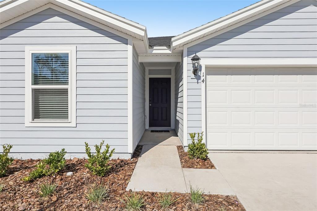 The exterior of a light blue house features a dark front door and garage — 14 DILLY COURT, PALM COAST, FL