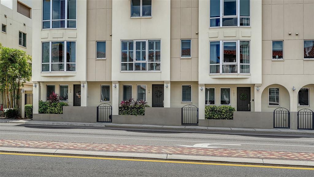 A row of three-story townhouses with dark doors, large windows, and small front courtyards — 235 COCOANUT AVENUE UNIT 106-B, SARASOTA, FL