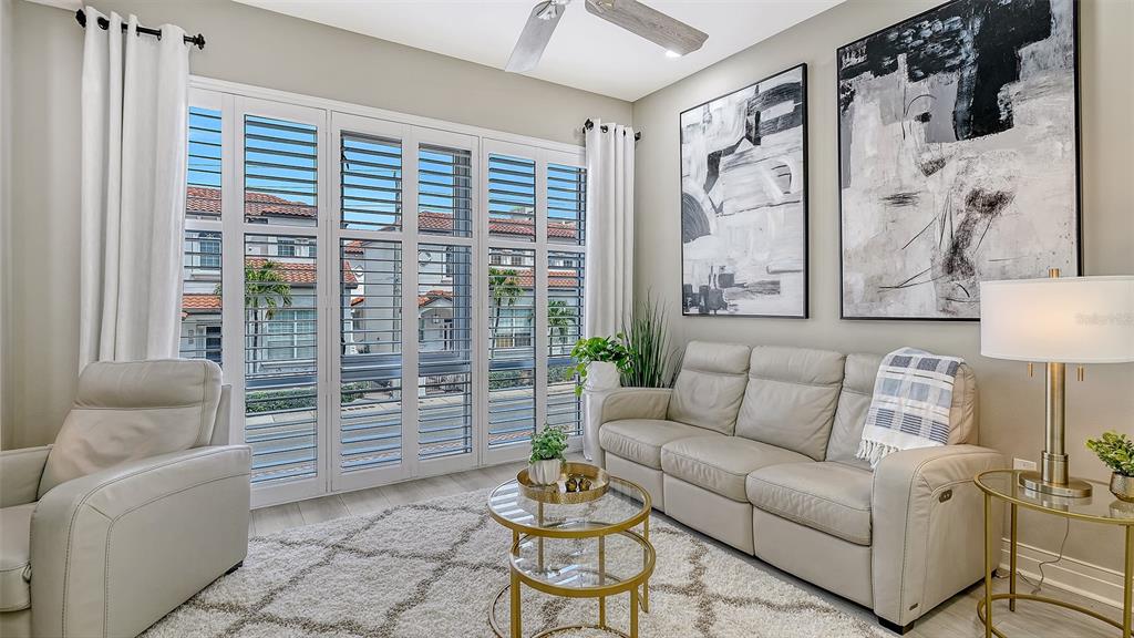 A living room features a light-colored sofa, a glass coffee table, and large window shutters — 235 COCOANUT AVENUE UNIT 106-B, SARASOTA, FL
