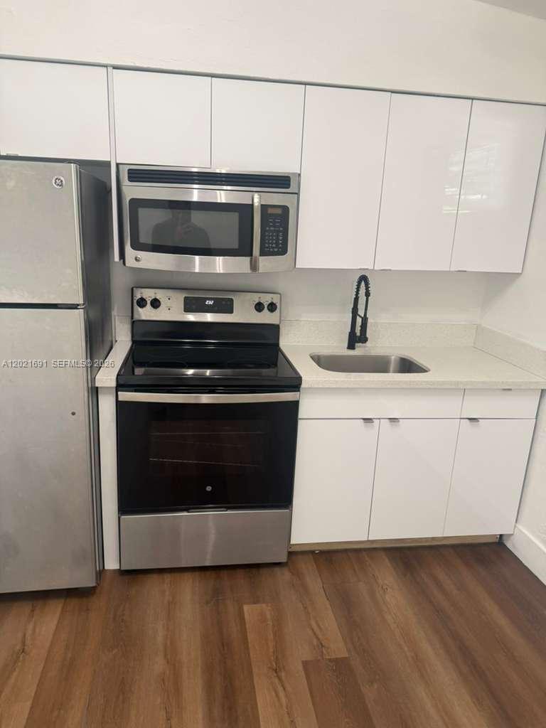 A kitchen features white cabinets, stainless steel appliances, a sink, and wood-look flooring — 2029 Washington Ave # 2, Opa-Locka FL 33054, OPA-LOCKA, FL