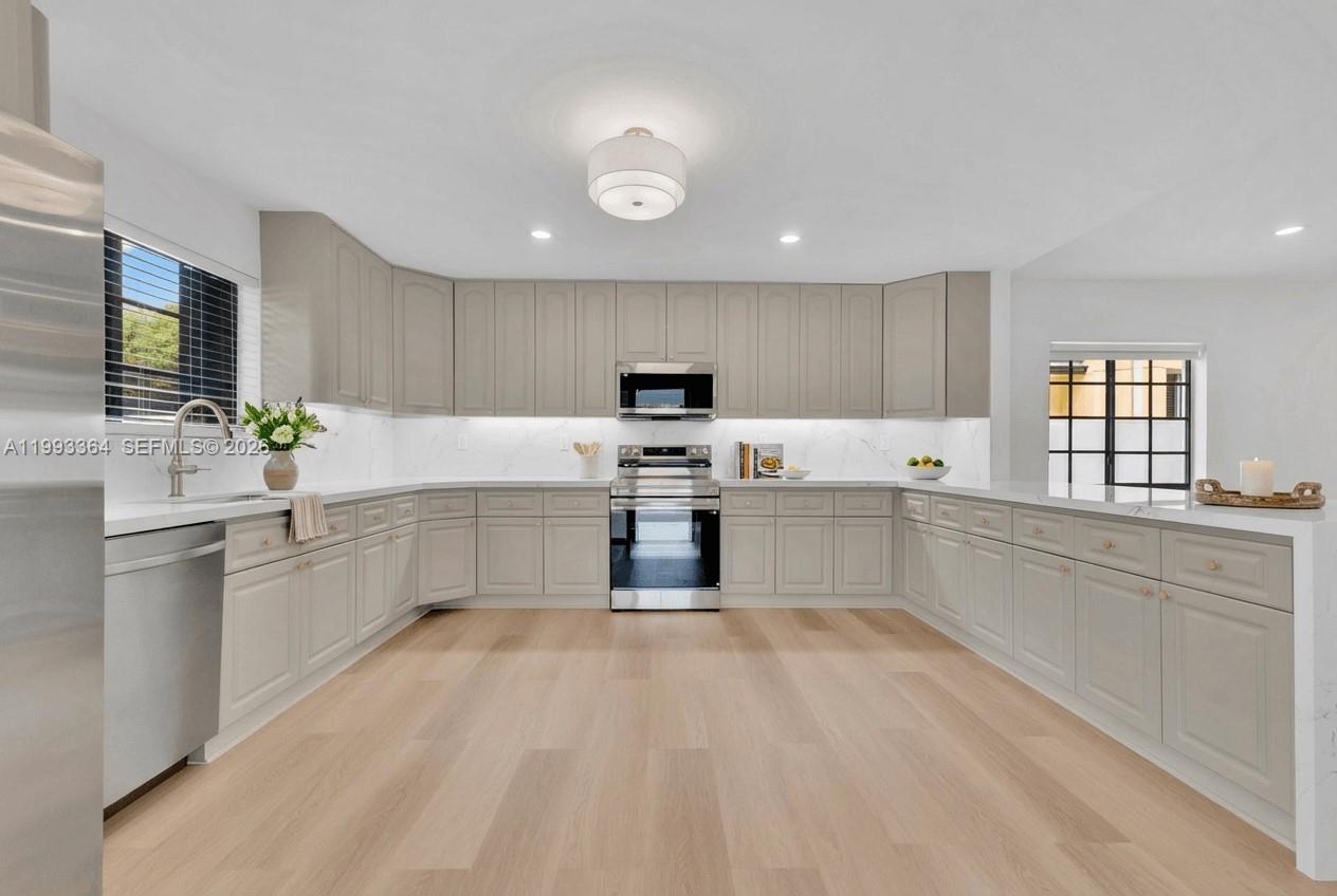 A modern kitchen features light gray cabinets, stainless steel appliances, and light wood flooring — 456 SW 20th Rd # 458, Miami FL 33129, MIAMI, FL