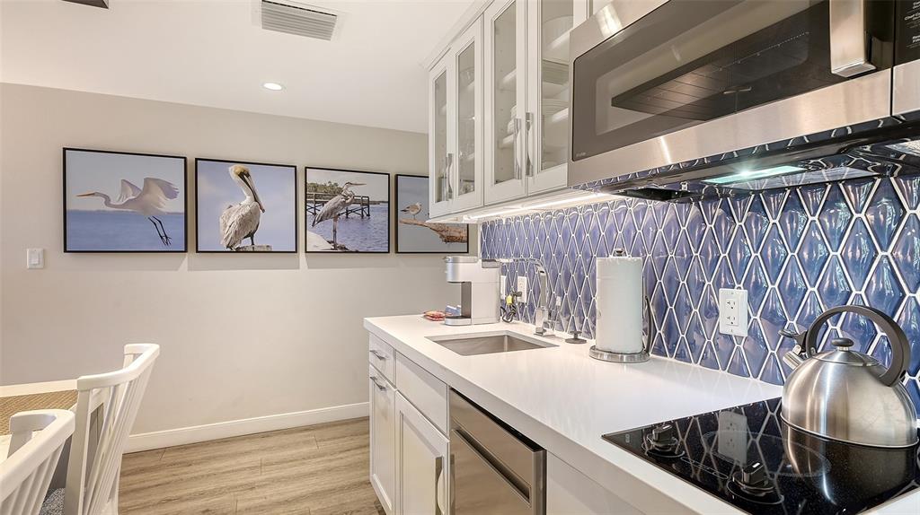 A kitchen features white cabinets, a blue diamond-patterned backsplash, and four bird-themed wall prints — 250 SANDS POINT ROAD UNIT 5101, LONGBOAT KEY, FL