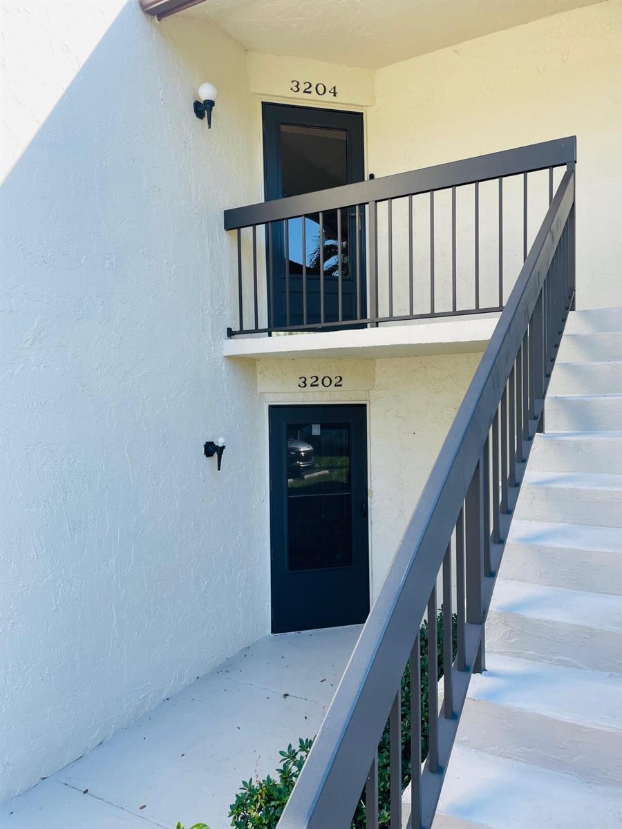 An exterior view shows two stacked apartment entrances with dark doors and a metal staircase — 3204 Perimeter Drive # 3204, FL 33467, FL