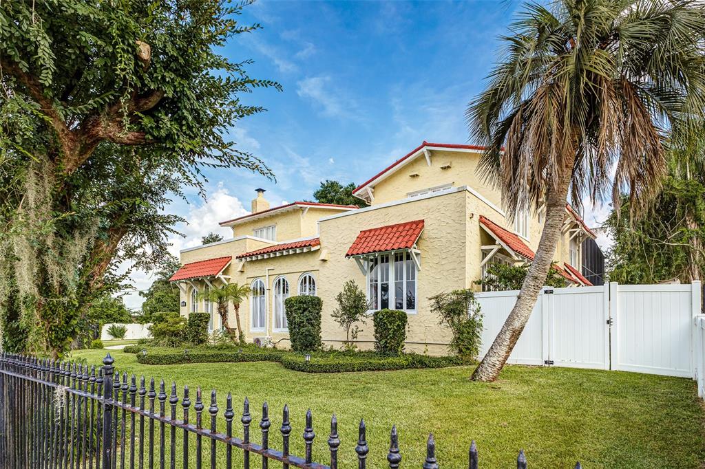A yellow stucco house with red tile roofs sits behind a black metal fence — 845 E EDGEWOOD DRIVE, LAKELAND, FL