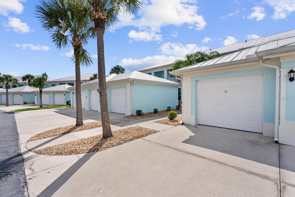 A row of light blue garages with white doors and metal roofs under palm trees — 5751 SABAL TRACE DRIVE UNIT 103B57, NORTH PORT, FL
