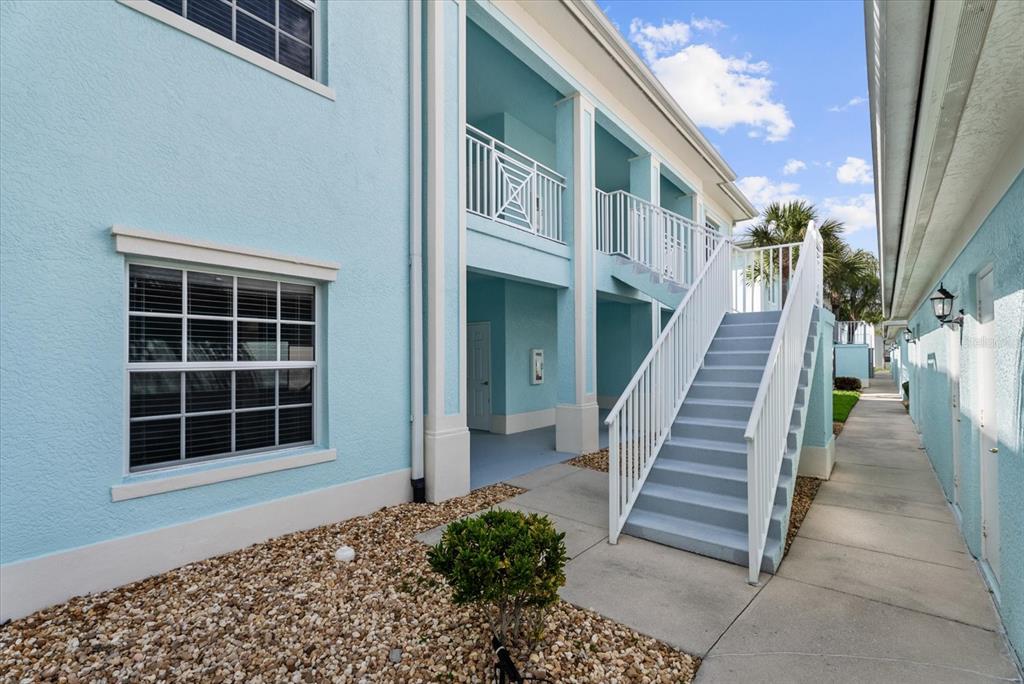 A light blue two-story building features an exterior staircase leading to an upper balcony — 5751 SABAL TRACE DRIVE UNIT 103B57, NORTH PORT, FL