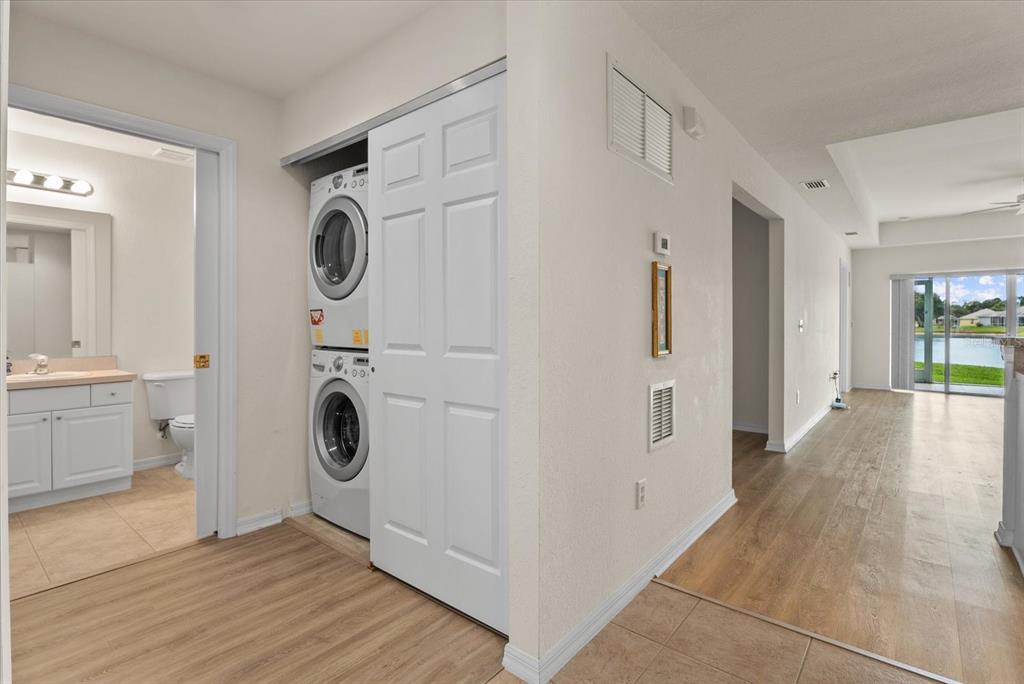 A hallway features a stacked washer and dryer, a bathroom entrance, and light wood flooring — 5751 SABAL TRACE DRIVE UNIT 103B57, NORTH PORT, FL