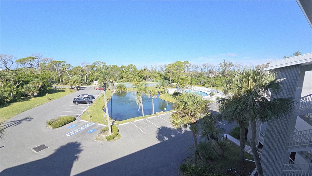 An elevated view shows a parking lot, a small pond with a fountain, and palm trees — 1401 S MCCALL ROAD UNIT 301A, ENGLEWOOD, FL
