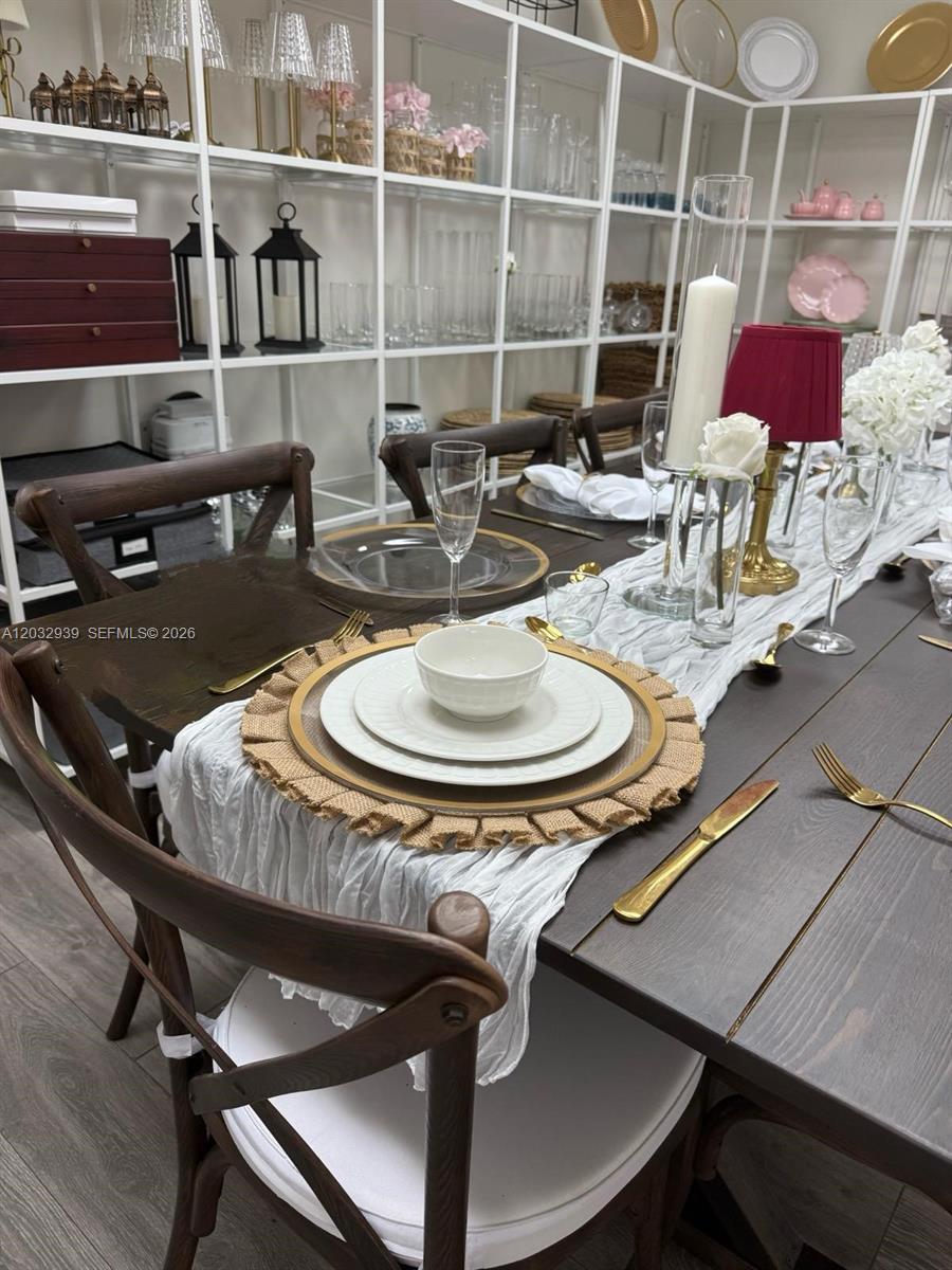 A dining table is set with white plates, gold cutlery, and a white runner — MEDLEY, FL