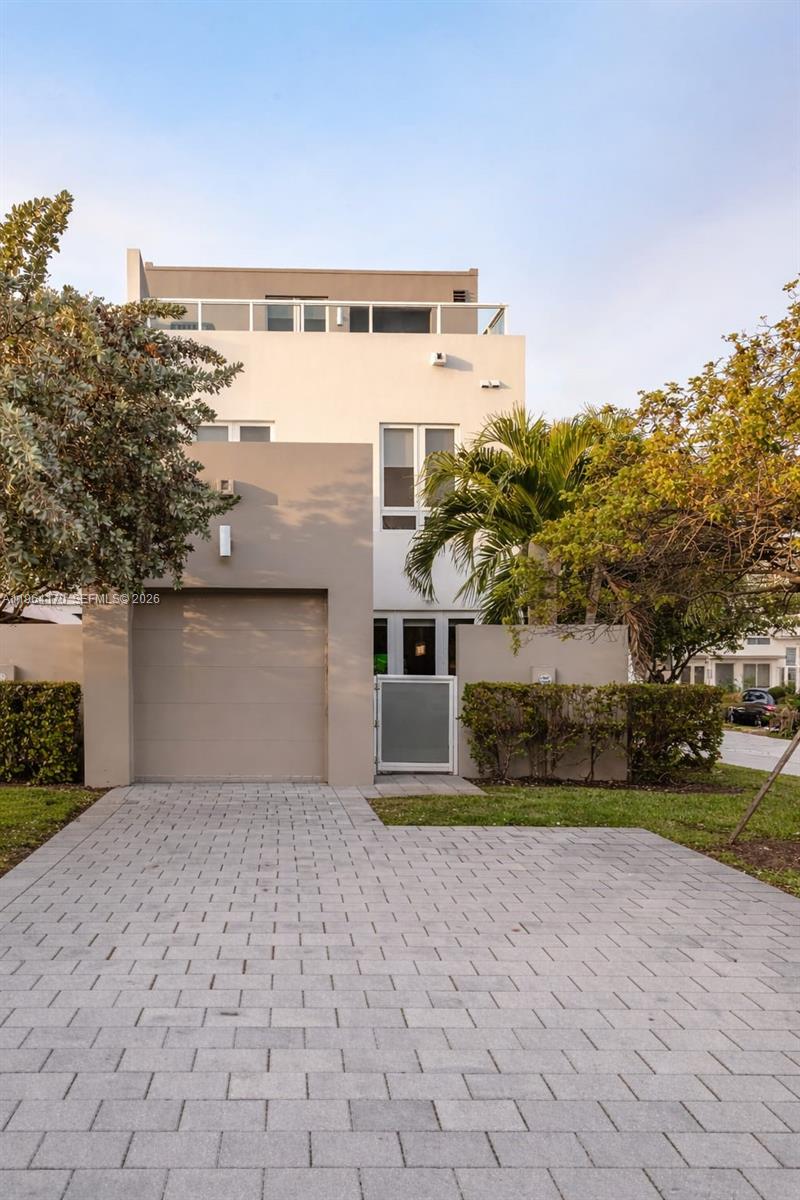 The exterior of a modern three-story townhouse features a paved driveway and a garage — 10464 NW 66th St, Doral FL 33178, DORAL, FL