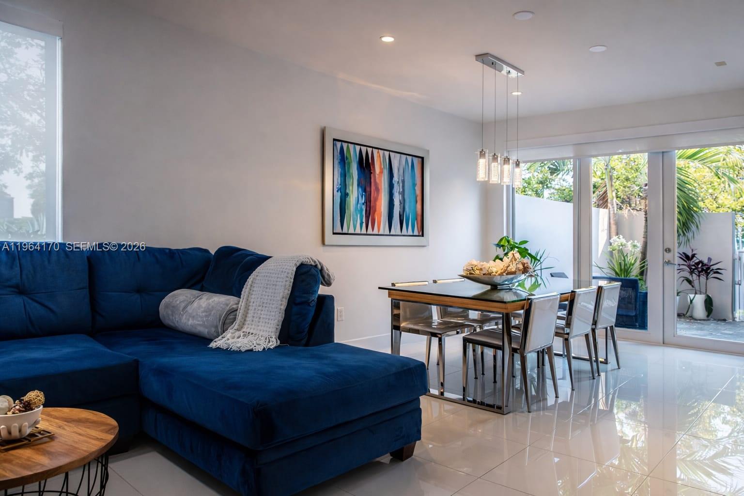 A living and dining area features a blue sectional sofa, glass table, and sliding doors — 10464 NW 66th St, Doral FL 33178, DORAL, FL