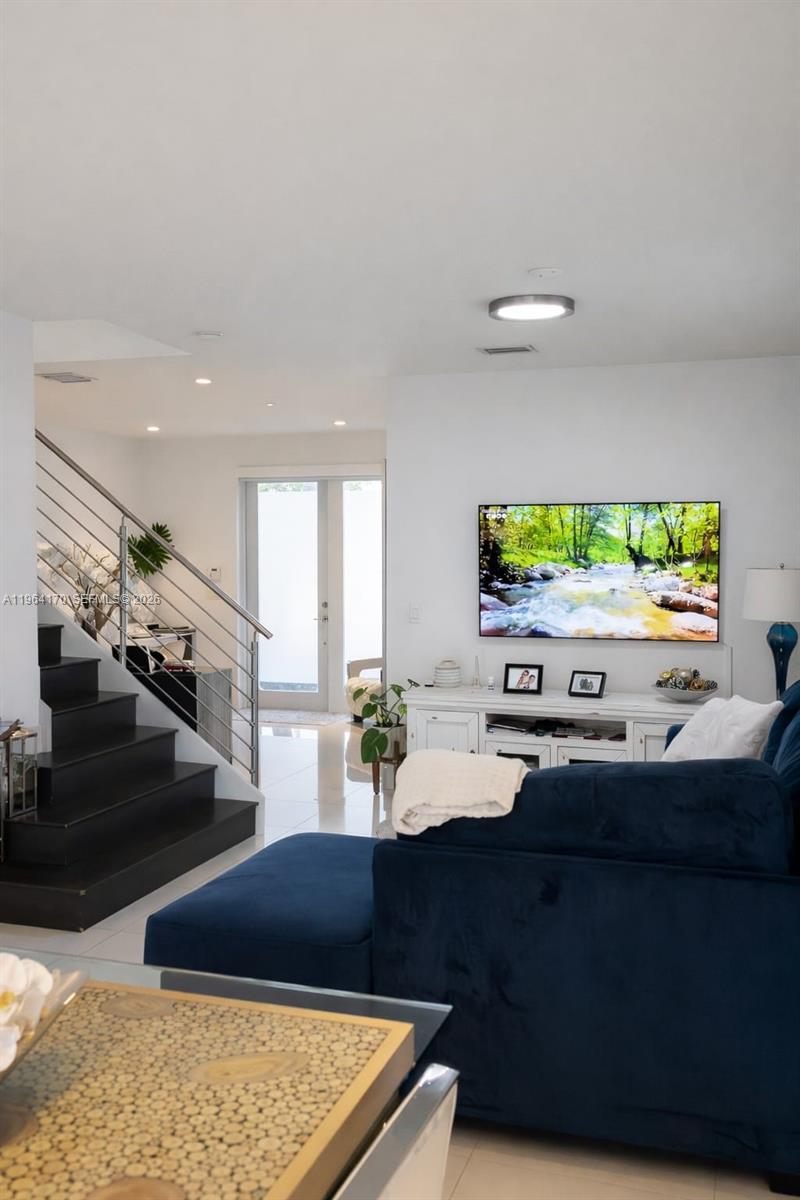 A living room features a blue sectional sofa, a wall-mounted television, and a staircase — 10464 NW 66th St, Doral FL 33178, DORAL, FL