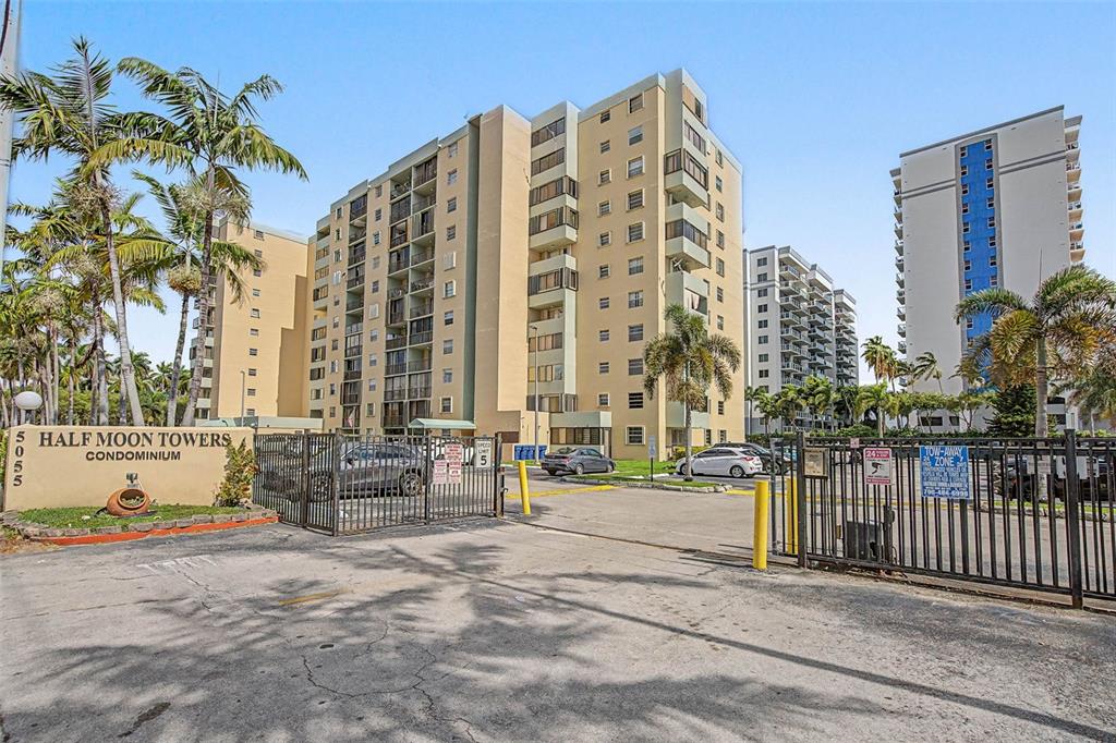 An exterior view of the Half Moon Towers condominium complex with palm trees and gated entrance — 5055 NW 7TH STREET UNIT 112, MIAMI, FL