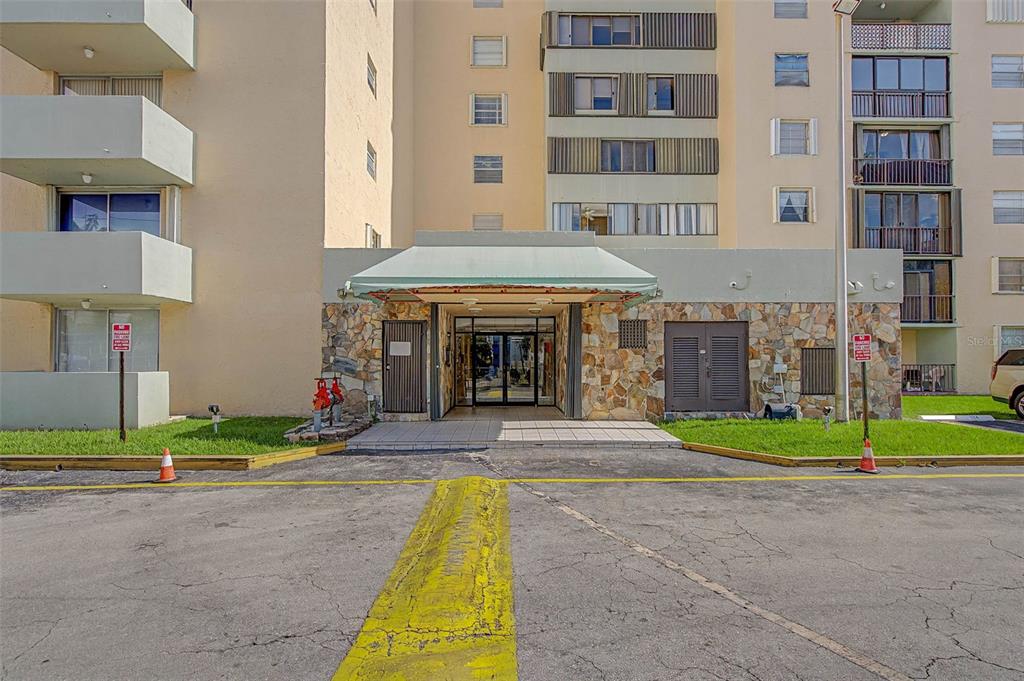 The exterior view shows the stone-faced entrance of a multi-story apartment building with balconies — 5055 NW 7TH STREET UNIT 112, MIAMI, FL