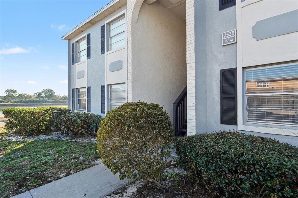A two-story apartment building exterior with a central staircase and landscaping — 2535 N ALAFAYA TRAIL UNIT 66, ORLANDO, FL