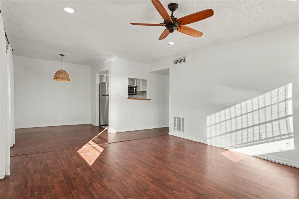 A living room with wood-look flooring, a ceiling fan, and a pass-through to the kitchen — 2535 N ALAFAYA TRAIL UNIT 66, ORLANDO, FL