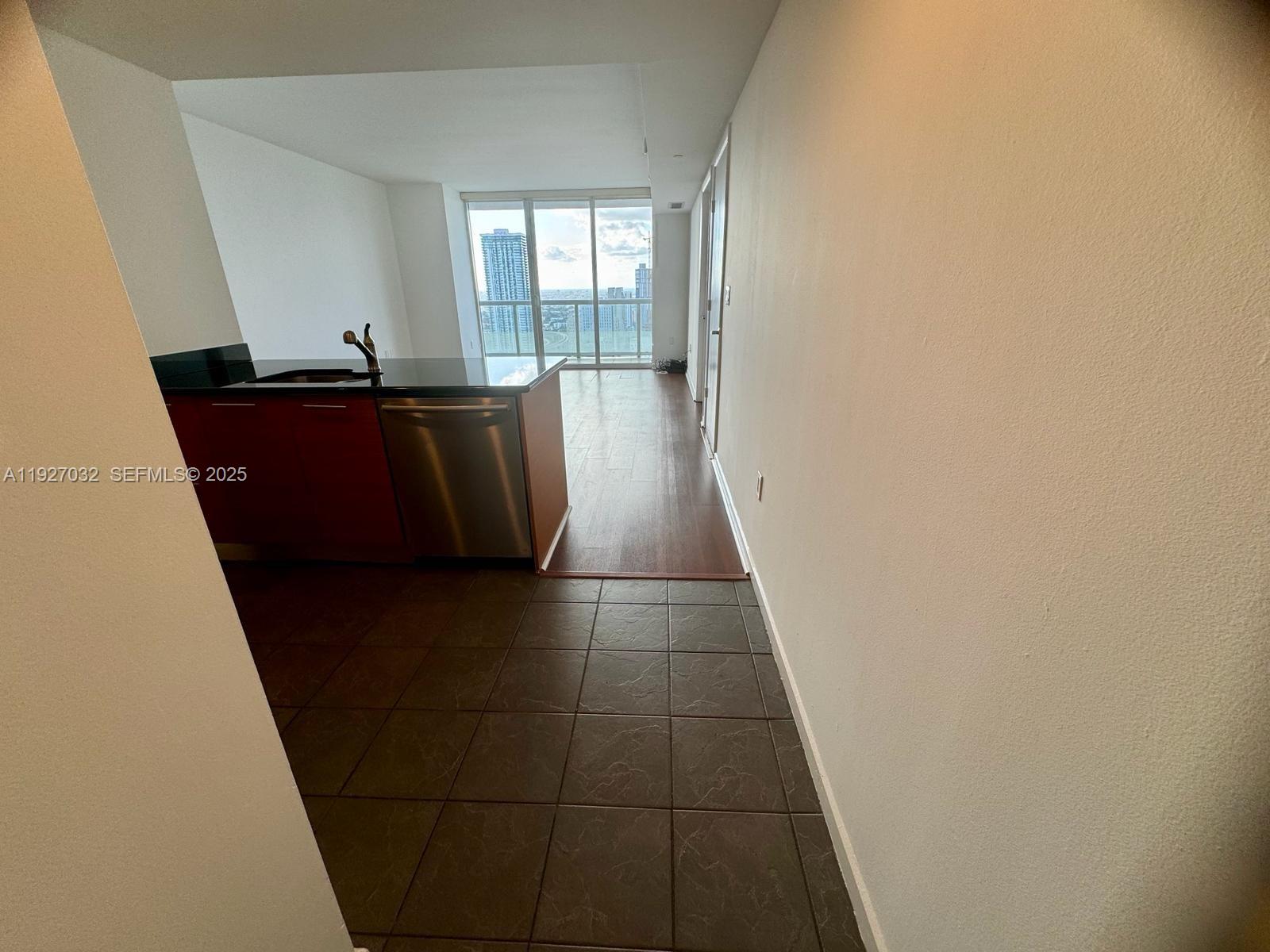 A kitchen with dark cabinets and stainless steel appliances transitions to a wood-floored living area — 50 BISCAYNE Blvd # 3807, Miami FL 33132, MIAMI, FL