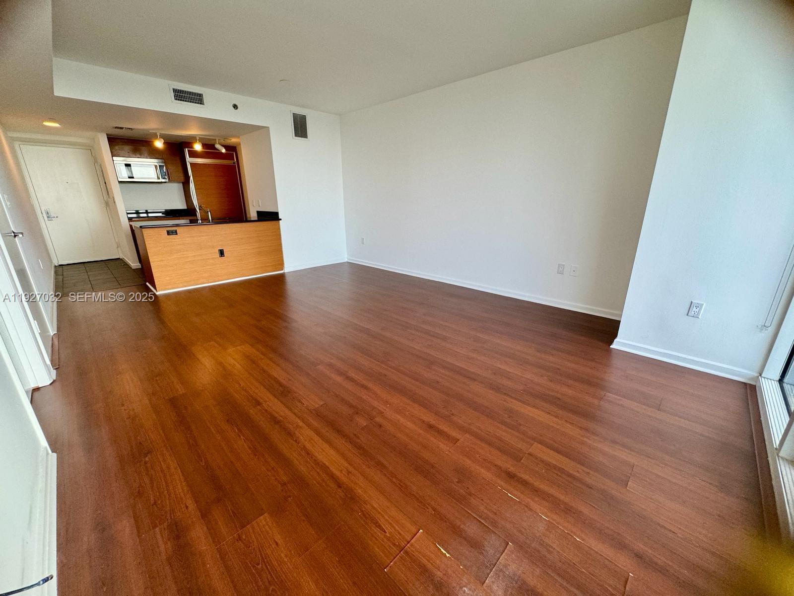 An open-concept living area features wood-look flooring and an adjacent kitchen with a breakfast bar — 50 BISCAYNE Blvd # 3807, Miami FL 33132, MIAMI, FL