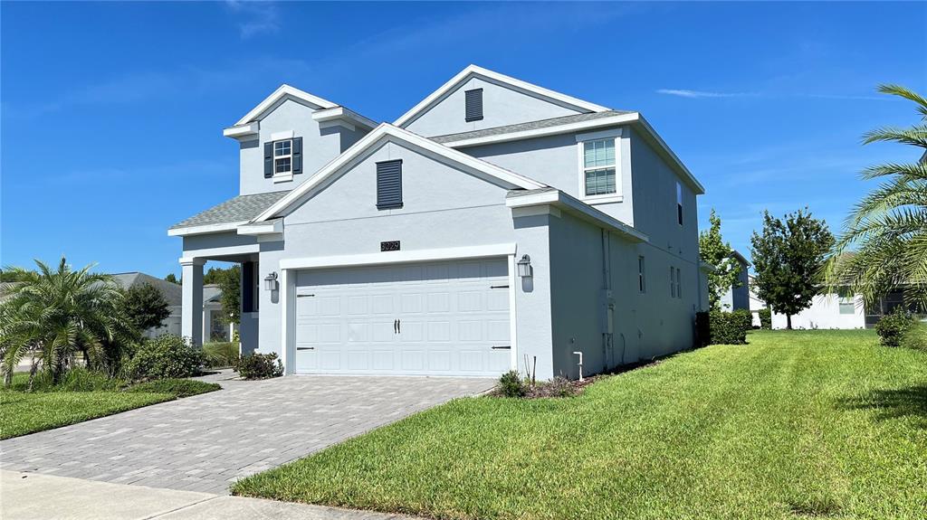 A two-story house with a light gray exterior, a two-car garage, and a paved driveway — 3029 PRELUDE LANE, KISSIMMEE, FL
