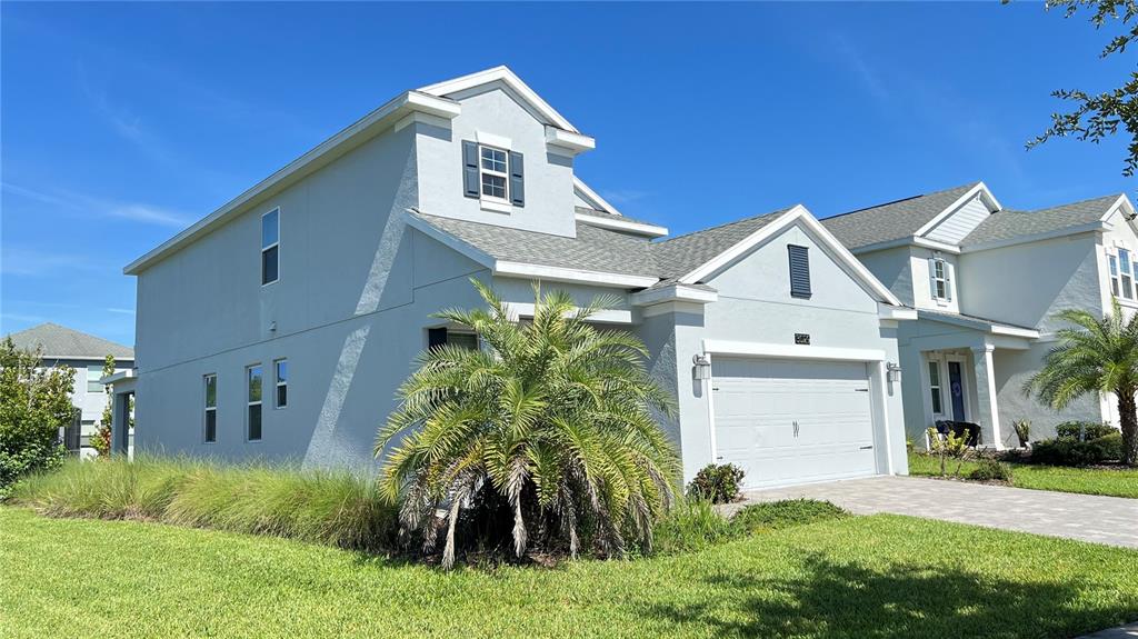 A two-story light blue house with a two-car garage and a front palm tree — 3029 PRELUDE LANE, KISSIMMEE, FL