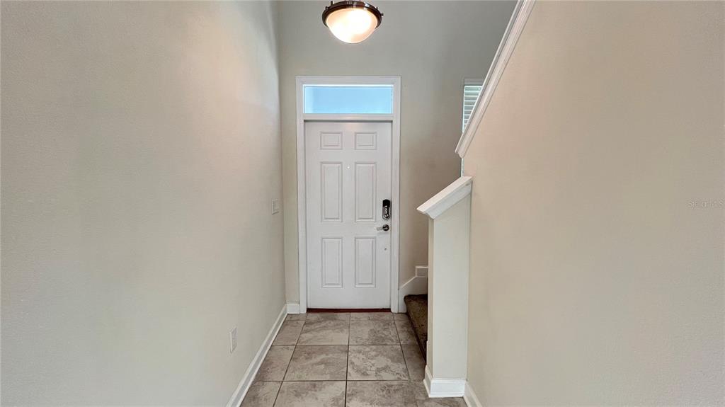 An entryway features a white front door, tile flooring, and a staircase with a railing — 3029 PRELUDE LANE, KISSIMMEE, FL